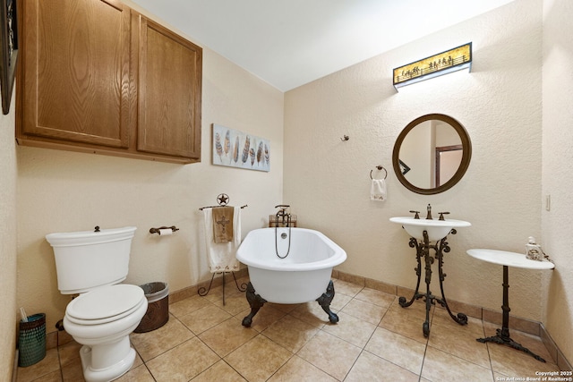 bathroom with tile patterned floors, a freestanding tub, toilet, and baseboards