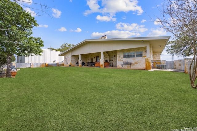 back of property with a gate, a lawn, and fence