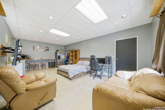 bedroom with stainless steel fridge with ice dispenser, a drop ceiling, and recessed lighting