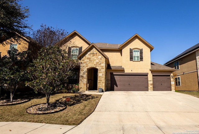 french country home with a garage, concrete driveway, stone siding, and stucco siding