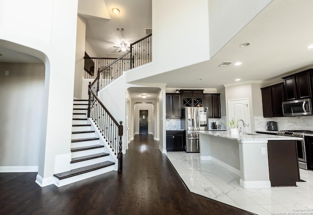 kitchen featuring appliances with stainless steel finishes, arched walkways, marble finish floor, and baseboards