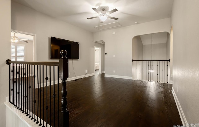 empty room with a ceiling fan, wood finished floors, attic access, and baseboards