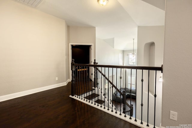 hall featuring visible vents, vaulted ceiling, an upstairs landing, wood finished floors, and baseboards