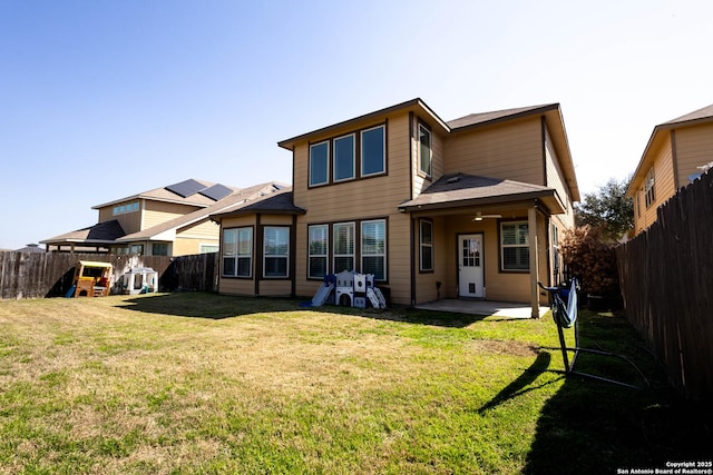 back of house featuring a patio area, a fenced backyard, a yard, and a playground