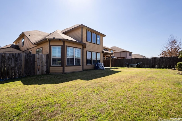 back of house featuring a lawn and a fenced backyard