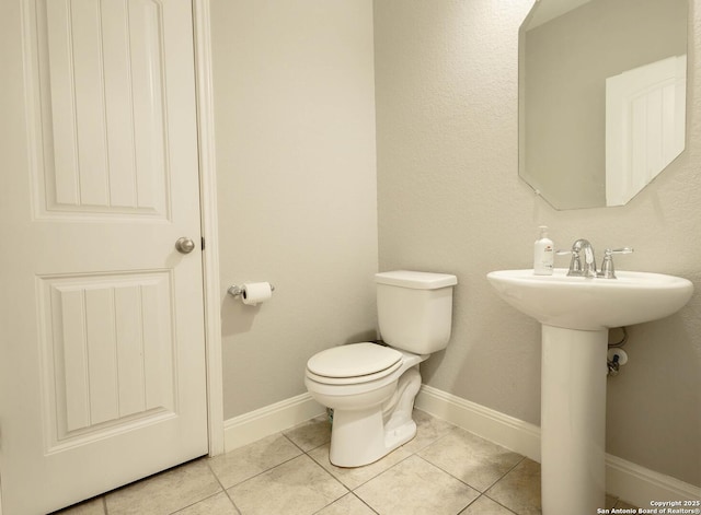 bathroom featuring a sink, tile patterned flooring, toilet, and baseboards