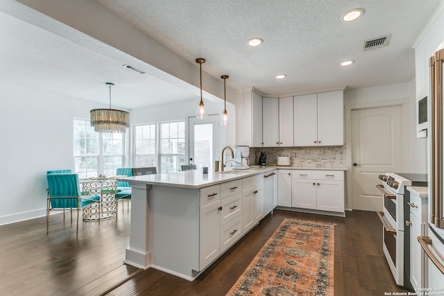 kitchen with visible vents, dark wood finished floors, range with two ovens, decorative backsplash, and a peninsula