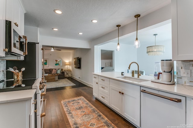 kitchen featuring dark wood-style flooring, open floor plan, white cabinets, a sink, and white appliances