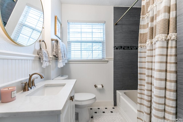 bathroom featuring a wainscoted wall, shower / bath combo with shower curtain, vanity, and toilet