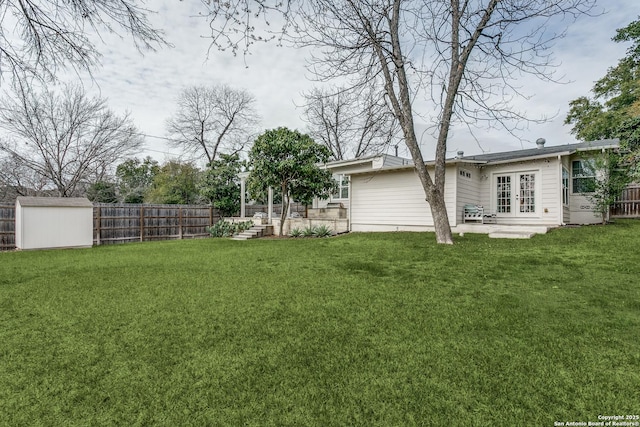 view of yard featuring french doors, an outdoor structure, and a fenced backyard