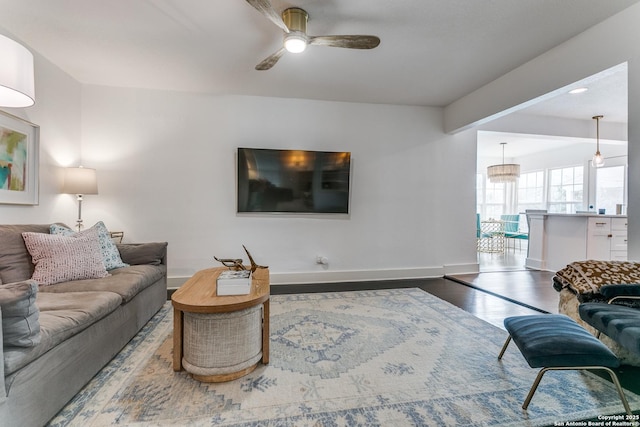 living area with a ceiling fan, baseboards, and wood finished floors