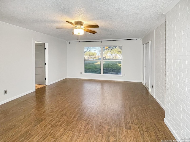 empty room with dark wood-style flooring, ornamental molding, ceiling fan, a textured ceiling, and baseboards