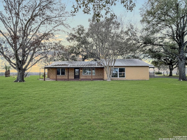 view of front of house with brick siding, metal roof, and a front yard