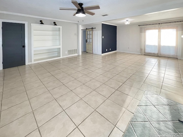 unfurnished room featuring ceiling fan, a barn door, ornamental molding, and visible vents