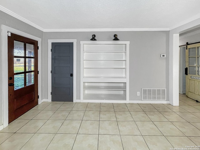 entryway with a textured ceiling, a barn door, visible vents, and crown molding