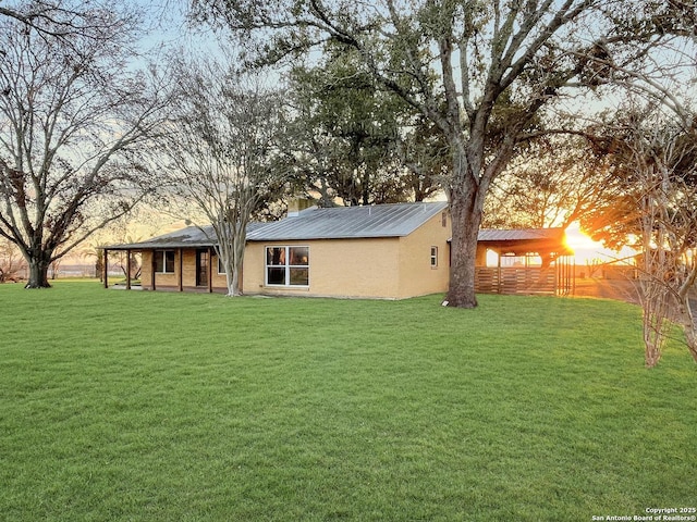 rear view of house with a yard, a chimney, fence, and stucco siding