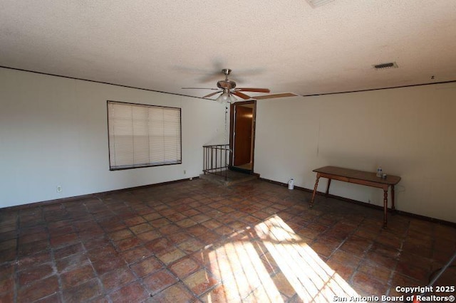 spare room featuring a ceiling fan, visible vents, and a textured ceiling