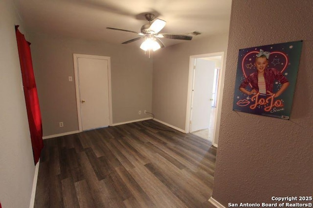 empty room featuring ceiling fan, wood finished floors, and baseboards