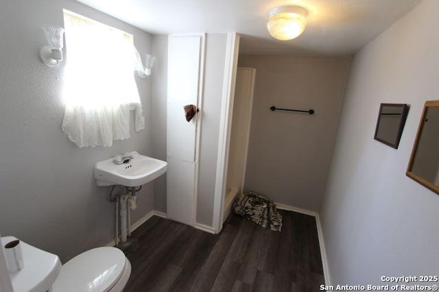 bathroom with wood finished floors, toilet, and baseboards