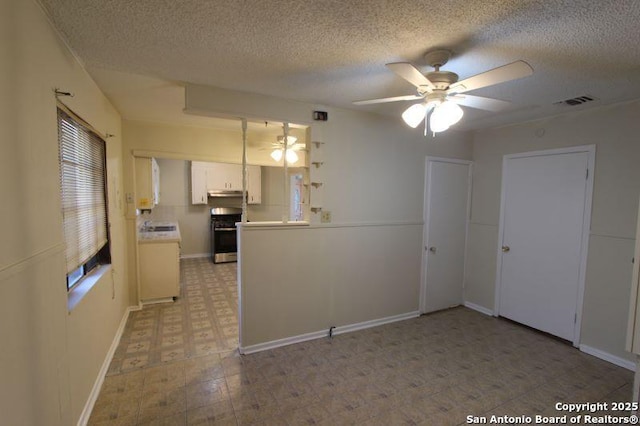 kitchen featuring a ceiling fan, white cabinets, light countertops, stainless steel range with gas cooktop, and light floors