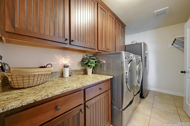 laundry room featuring washer and clothes dryer, visible vents, cabinet space, light tile patterned flooring, and a textured ceiling