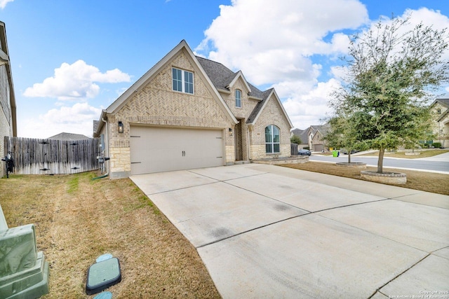 traditional home featuring concrete driveway, brick siding, a front yard, and fence