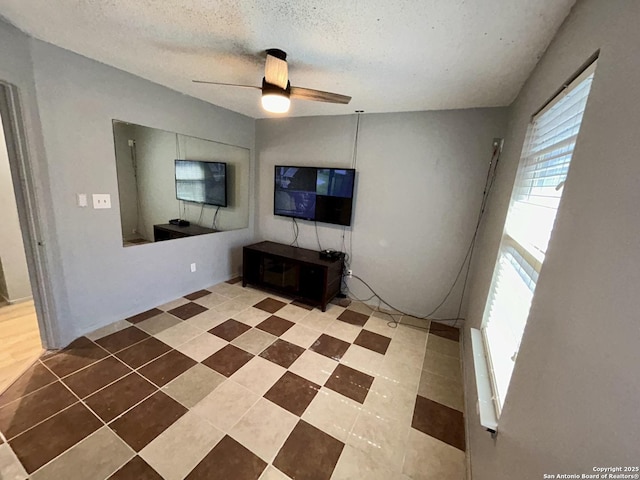 unfurnished living room with ceiling fan, a textured ceiling, and tile patterned floors