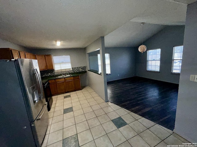 kitchen featuring brown cabinets, light tile patterned floors, dark countertops, and stainless steel refrigerator with ice dispenser