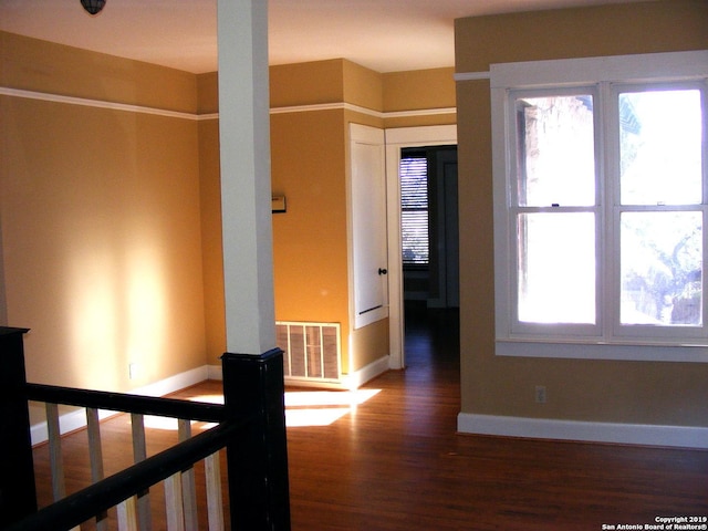 hall featuring a healthy amount of sunlight, visible vents, an upstairs landing, and wood finished floors