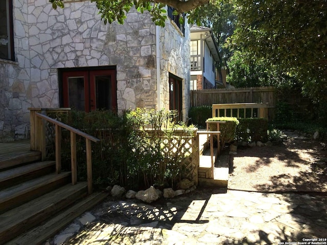 view of side of home with stone siding and fence