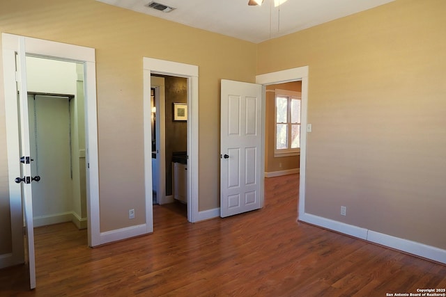 unfurnished bedroom featuring baseboards, visible vents, wood finished floors, a spacious closet, and a closet