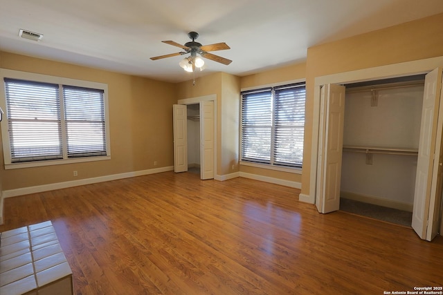 unfurnished bedroom with baseboards, two closets, visible vents, and light wood-style floors