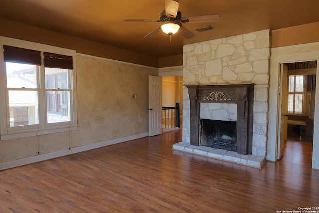 unfurnished living room featuring a ceiling fan, a fireplace, visible vents, and wood finished floors