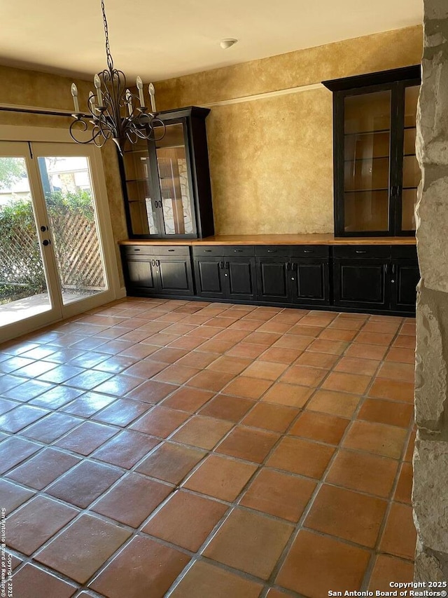 empty room featuring a chandelier and light tile patterned flooring