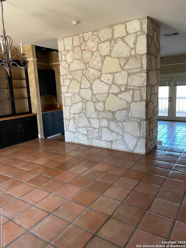 unfurnished living room with tile patterned flooring, visible vents, and french doors