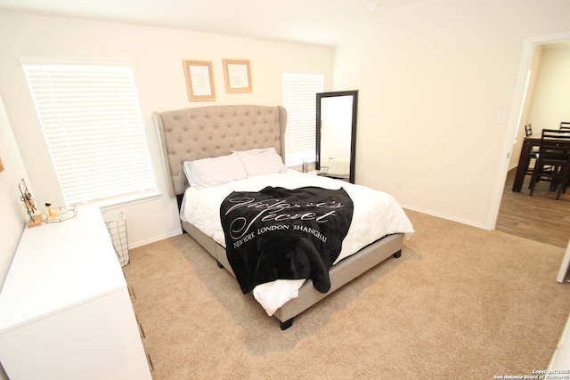 bedroom with baseboards and light colored carpet