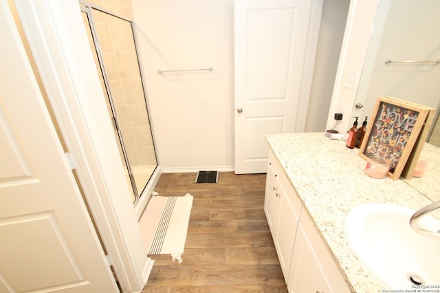 bathroom featuring wood finished floors, vanity, baseboards, radiator, and a stall shower