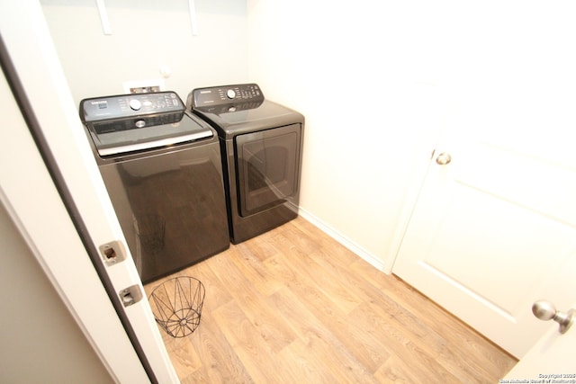 laundry room featuring light wood finished floors, laundry area, separate washer and dryer, and baseboards