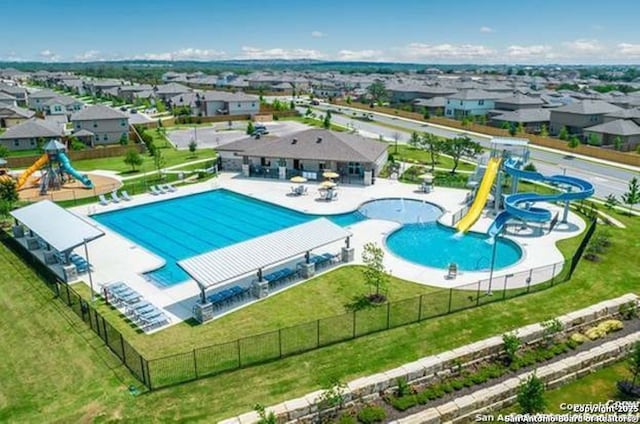 community pool with a patio area, fence, a water slide, and playground community