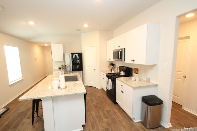 kitchen featuring black gas range, dark wood-style flooring, a sink, visible vents, and stainless steel microwave