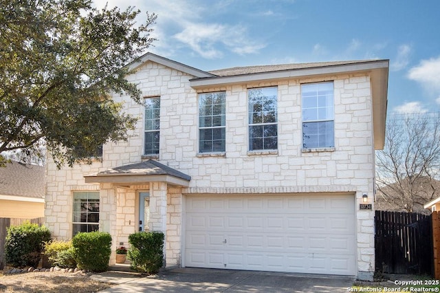 view of front of home featuring roof with shingles, concrete driveway, an attached garage, fence, and stone siding