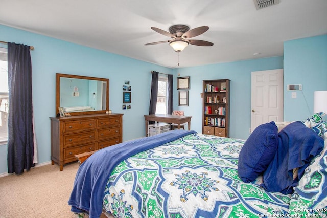 bedroom with light carpet, ceiling fan, visible vents, and baseboards