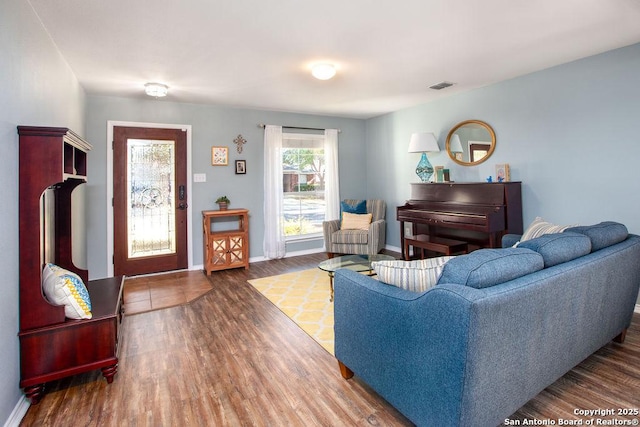 living room featuring baseboards, visible vents, and wood finished floors