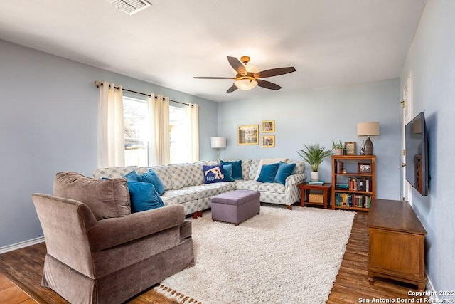 living area featuring baseboards, ceiling fan, visible vents, and wood finished floors