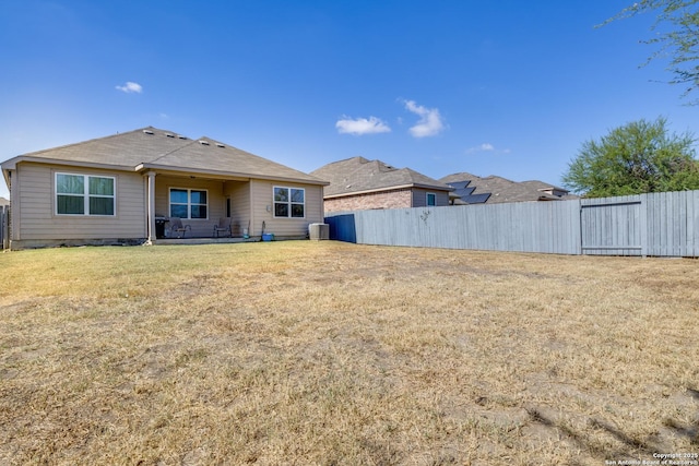 rear view of house featuring fence, cooling unit, and a yard