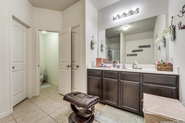 full bathroom featuring toilet, a stall shower, vanity, tile patterned flooring, and baseboards
