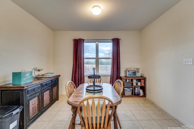 dining room with light tile patterned floors, a textured ceiling, and baseboards