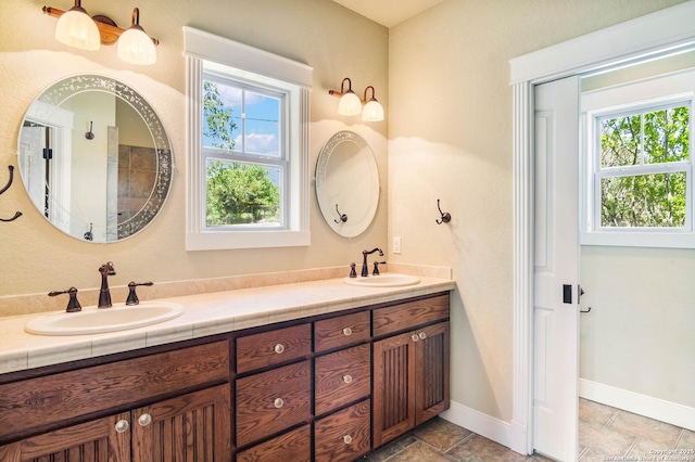 bathroom featuring double vanity, a sink, and baseboards