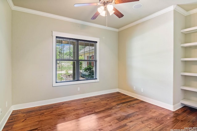 spare room featuring crown molding, ceiling fan, baseboards, wood finished floors, and built in shelves
