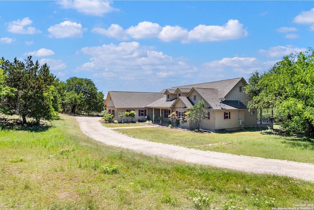 view of front of property with board and batten siding, dirt driveway, and a front lawn
